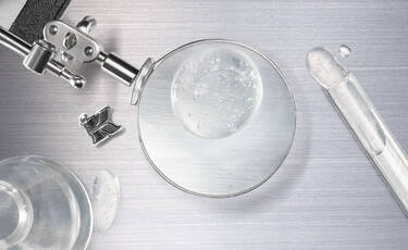 Close-up of retinol serum texture in a lab dish with dropper, representing Kiehl’s Pro-Retinol formula